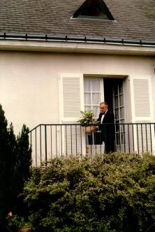Monsieur Leroux, devant la porte de sa maison, prépare les fleurs et les plantes